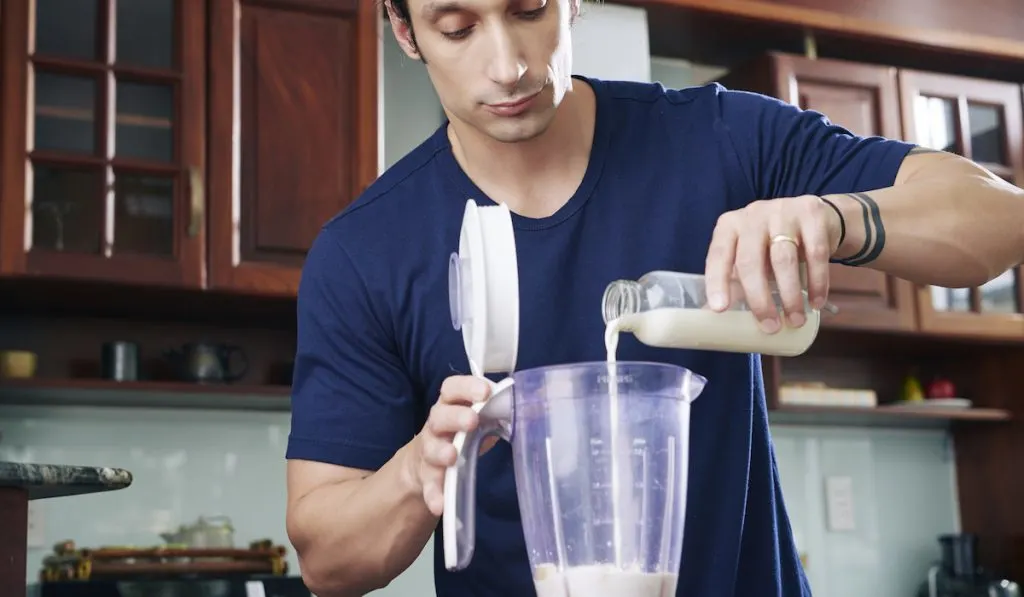 man putting milk in blender