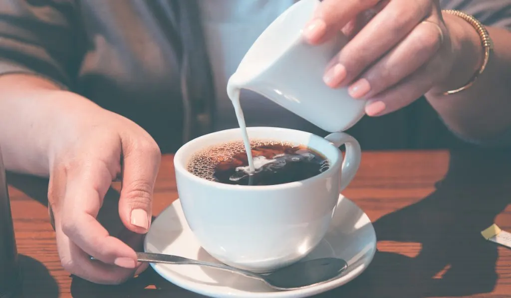 guy pouring cream on coffee