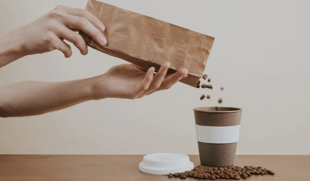 pouring coffee beans into cup