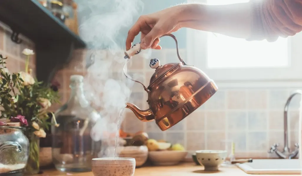 pouring hot water into cup of coffee