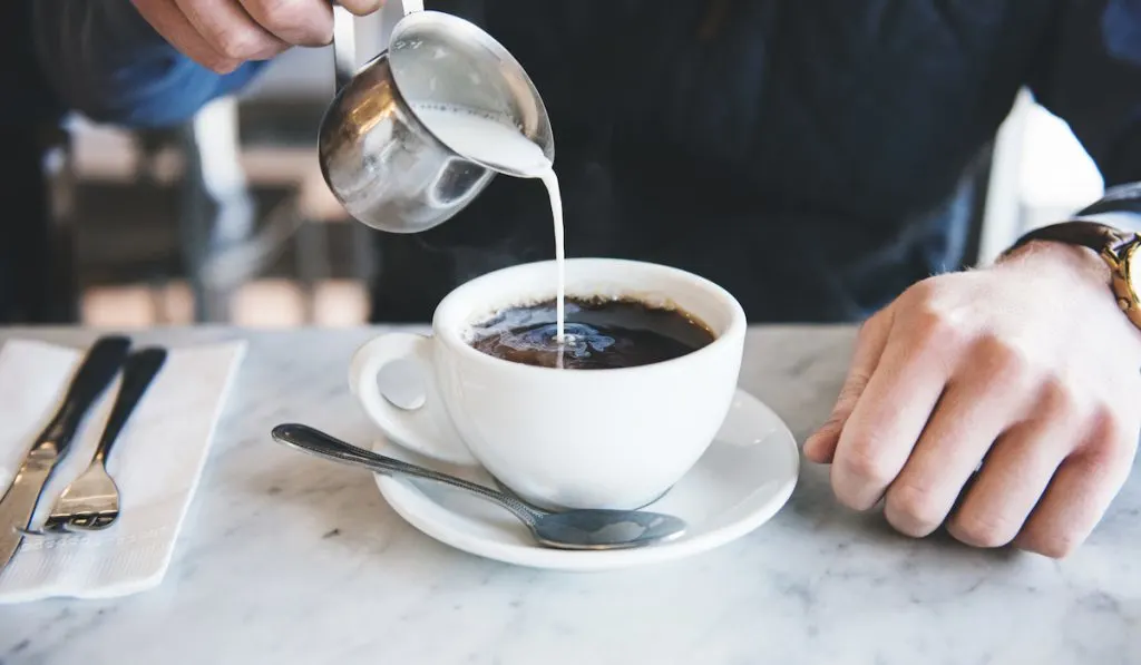 pouring milk to coffee