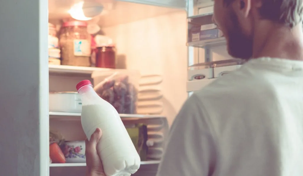 man getting a bottle of creamer from the fridge